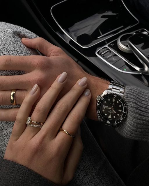 a woman's hand with two rings on her wrist next to a car steering wheel