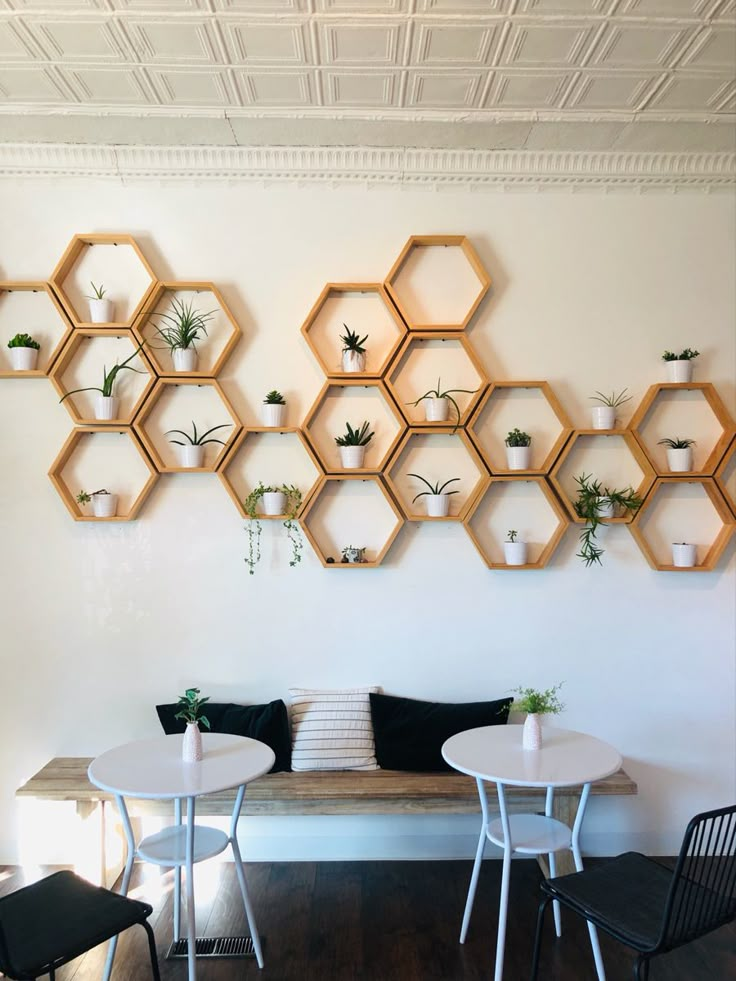 a room with several hexagonal shelves on the wall and two tables in front of them