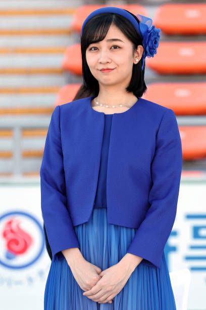 a woman standing in front of an orange and white sign wearing a blue dress with pleated skirt