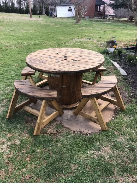 a wooden table and benches in the grass