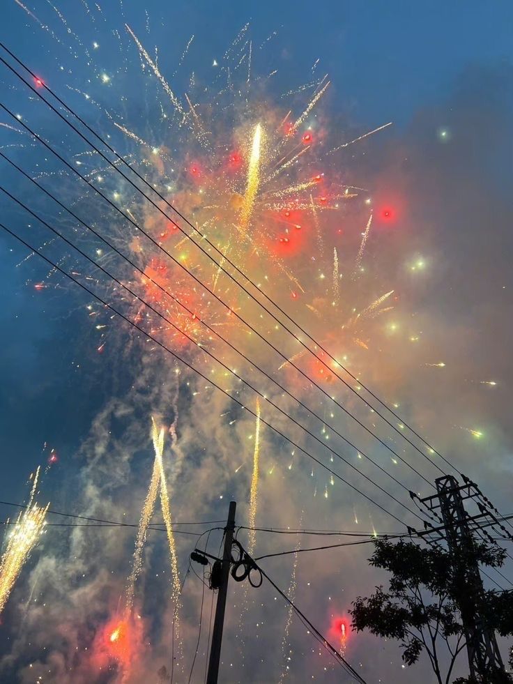 fireworks are lit up in the sky above power lines