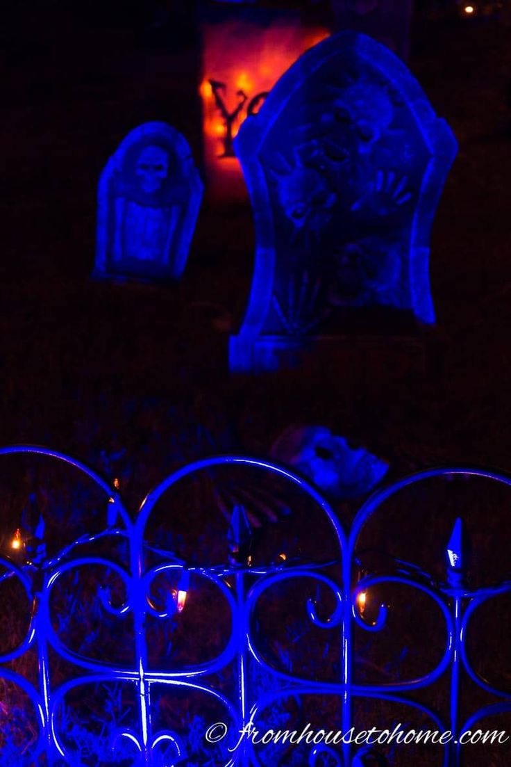 the cemetery is lit up with blue lights for halloween decorations, including tombstones and candles