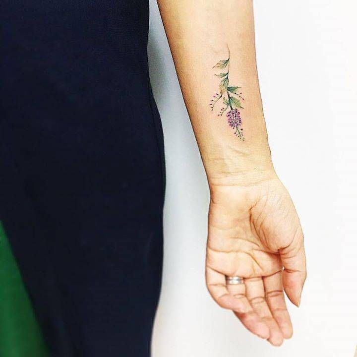 a woman's arm with a small flower tattoo on her left wrist and the other hand