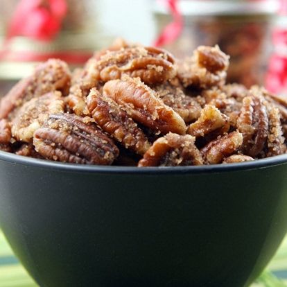 a black bowl filled with pecans sitting on top of a green tablecloth covered table