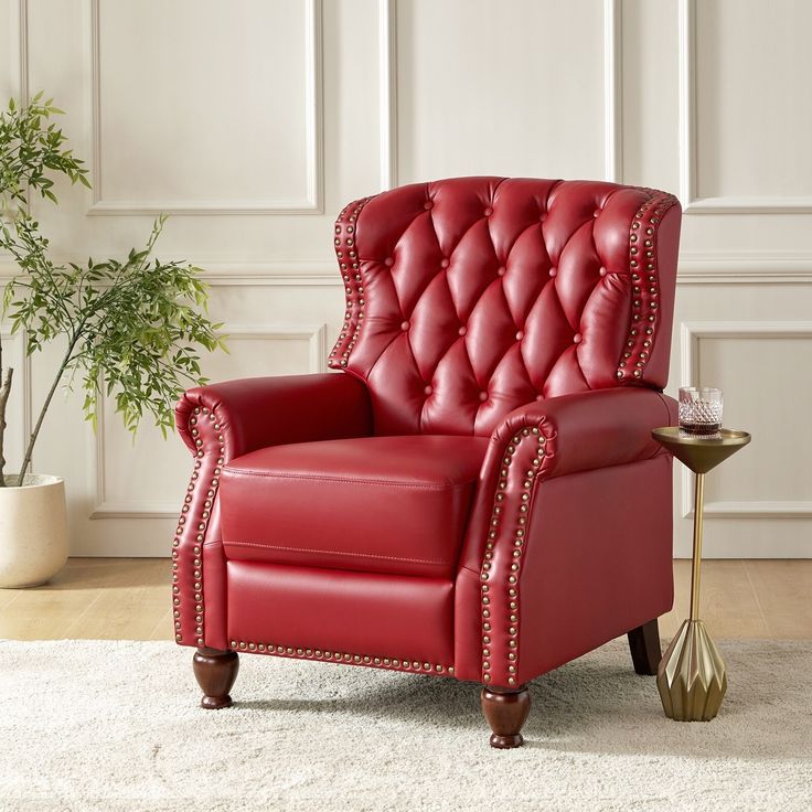 a red leather chair sitting on top of a white rug next to a potted plant