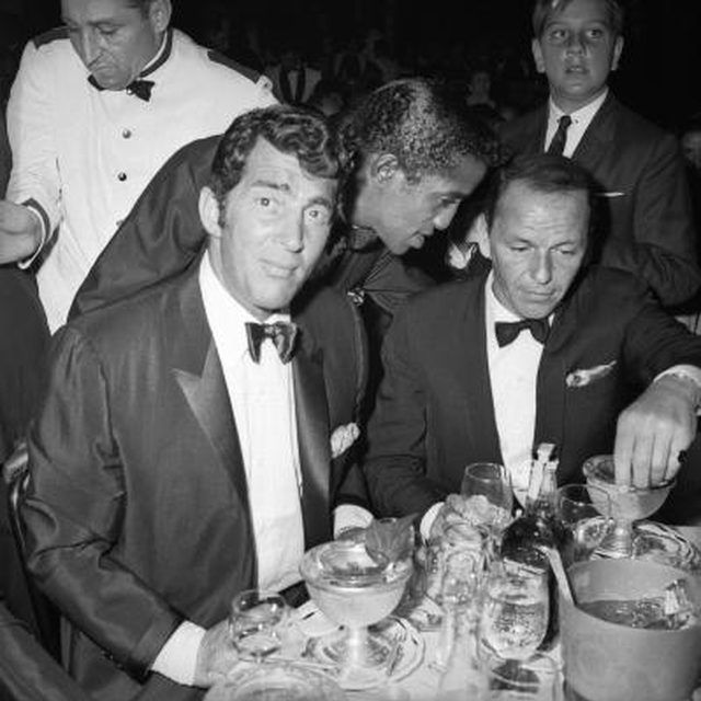 three men in tuxedos are sitting at a table