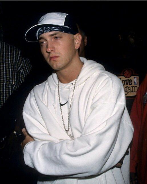 a man in a white hoodie is standing with his arms crossed