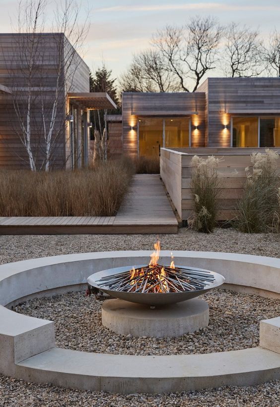 an outdoor fire pit in the middle of a gravel area with steps leading up to it