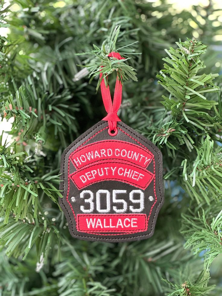 a red and black ornament hanging from a christmas tree with the words, howard county depty chief 2059 wallace