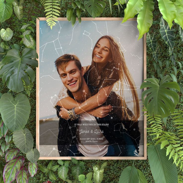 an image of a man and woman hugging in the middle of some green plants with leaves around them