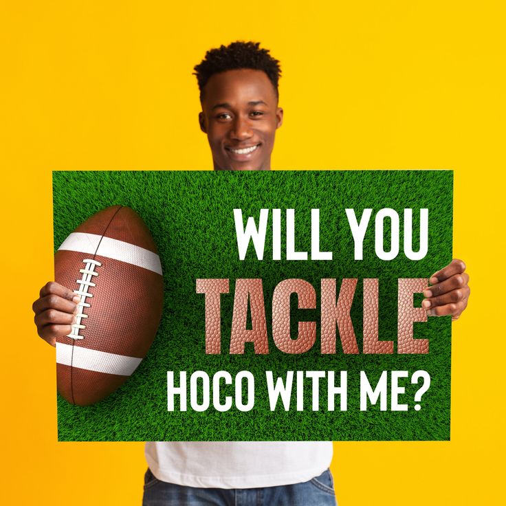 a man holding up a sign that says will you tackle hoco with me?