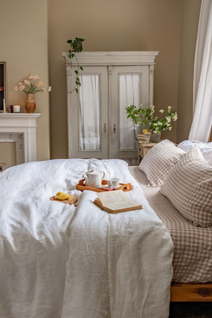 a bed with white linens and pillows on it in front of a bookcase