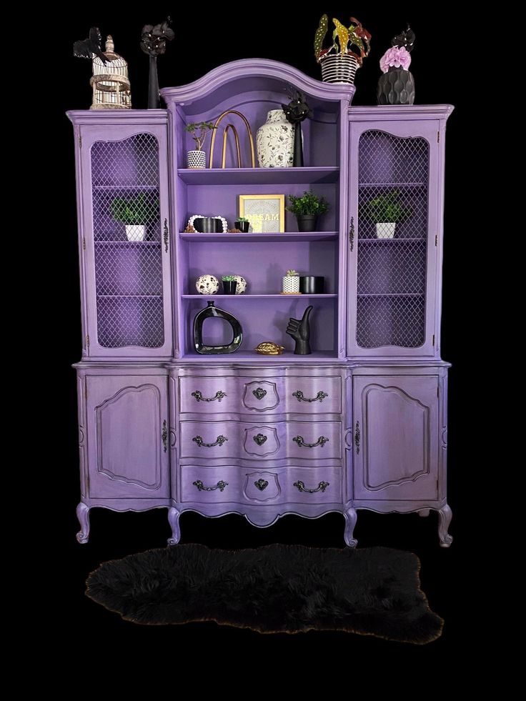 a purple china cabinet sitting on top of a black floor next to a sheepskin rug