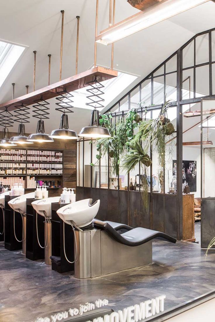 the interior of a salon with lots of chairs and plants on display in front of it