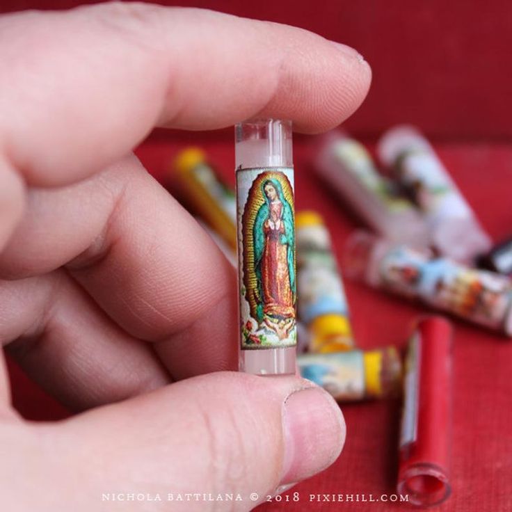 a hand holding a small glass tube with an image of the virgin mary on it