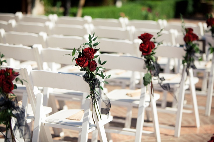 rows of white chairs with red roses on them