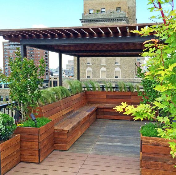 a wooden bench sitting on top of a roof next to trees and plants in planters