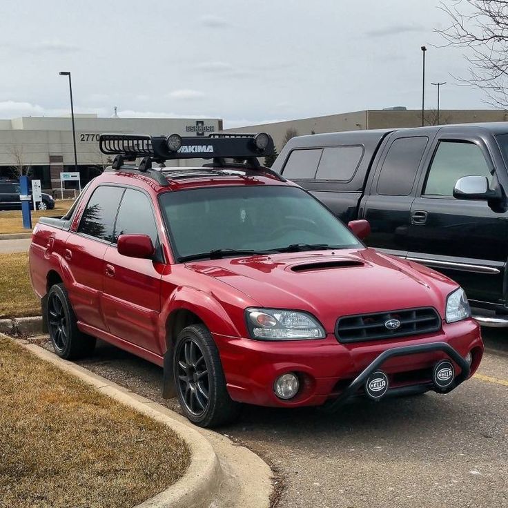 a red subarunt parked in a parking lot next to other cars and trucks