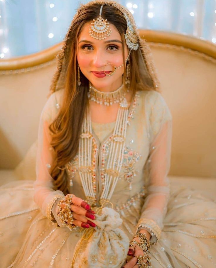 a woman sitting on top of a couch wearing a white dress and headpieces