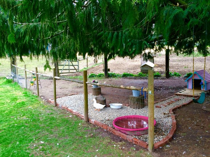 an outdoor play area in the middle of a yard with a bird feeder and fence