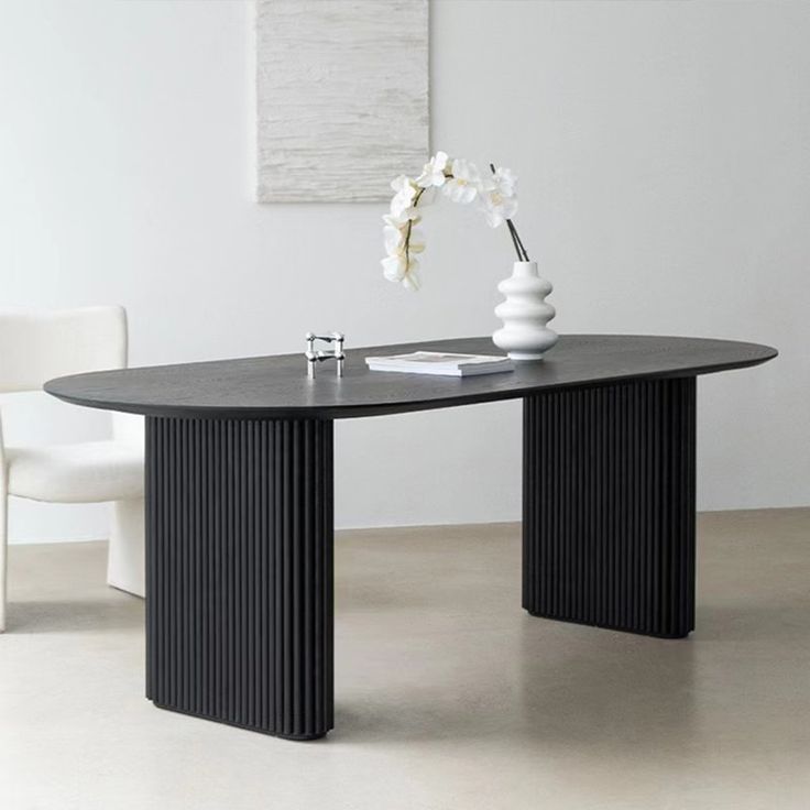 a black table with two white vases on top of it and a chair in the background