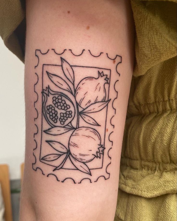 a tattoo on the arm of a woman with fruit and leaves in a square frame