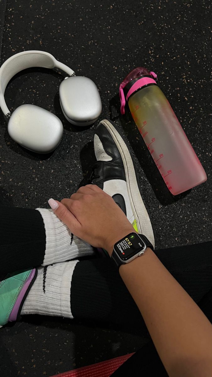 a woman's feet with headphones, water bottle and other items on the ground