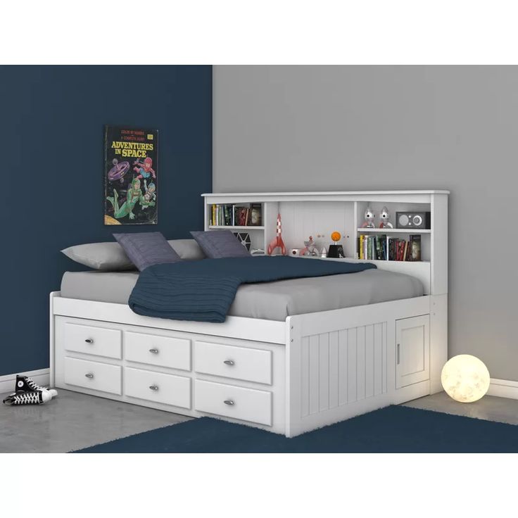 a white bed with drawers underneath it in a blue and gray room, next to a bookcase