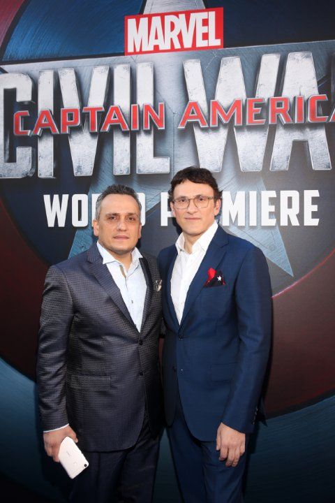 two men standing next to each other in front of a captain america sign at an event