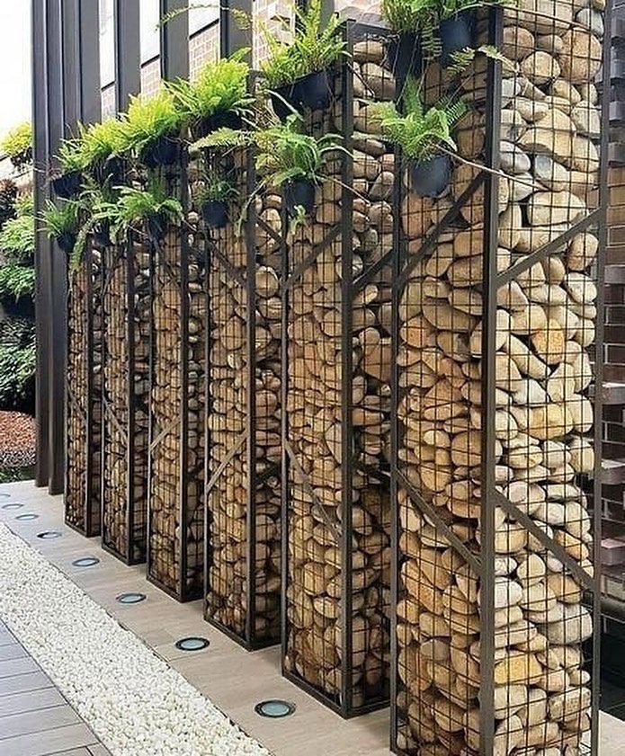 several stacks of logs with plants growing out of them on the side of a building