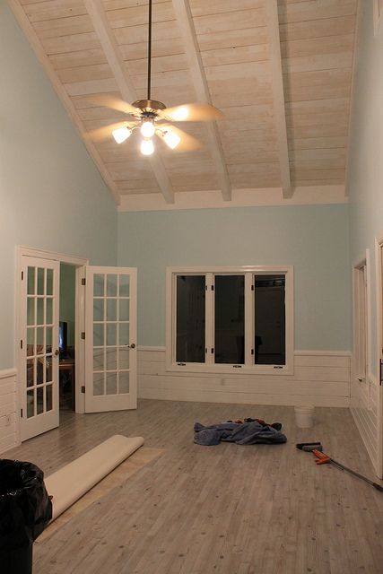 an empty room with white doors and wood flooring, all painted in light blue