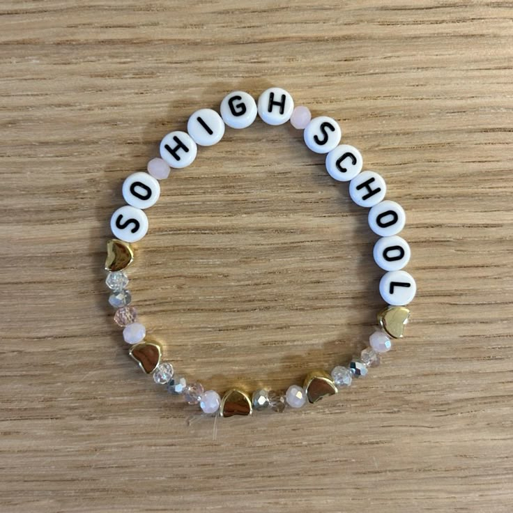 a white and gold beaded bracelet with the word school spelled in small letters on it