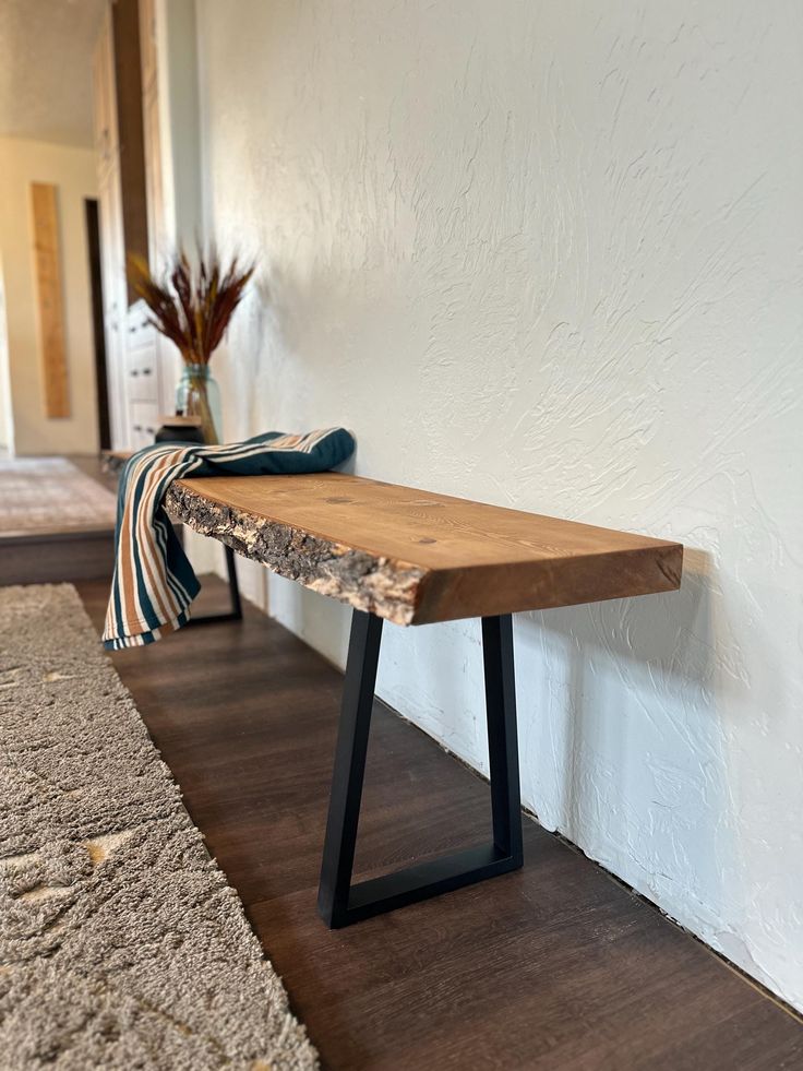 a wooden bench sitting on top of a hard wood floor next to a white wall