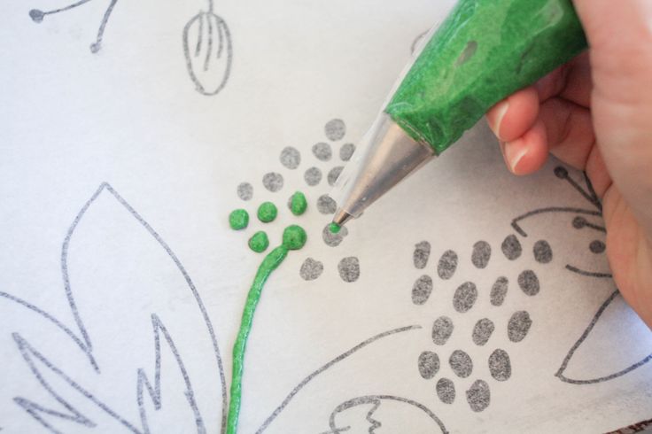 someone is drawing flowers on a piece of paper with crayons and a green marker