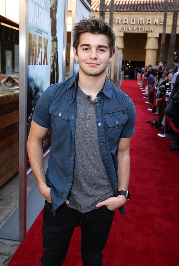 a young man standing on top of a red carpet