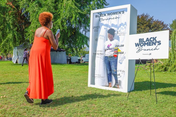 a woman in an orange dress standing next to a black women's rights sign