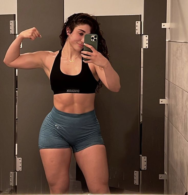 a woman taking a selfie with her cell phone in front of some lockers