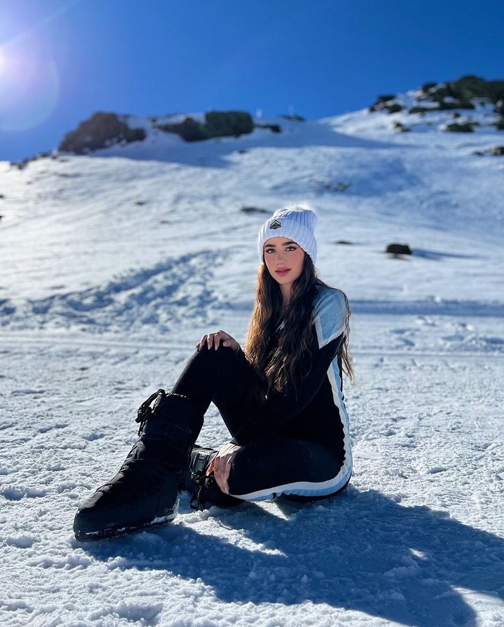 a woman sitting in the snow with her legs crossed