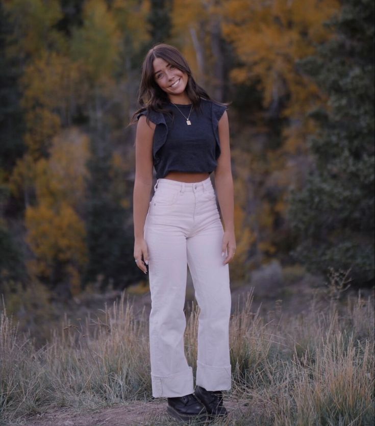 a woman standing in the grass with her hands on her hips