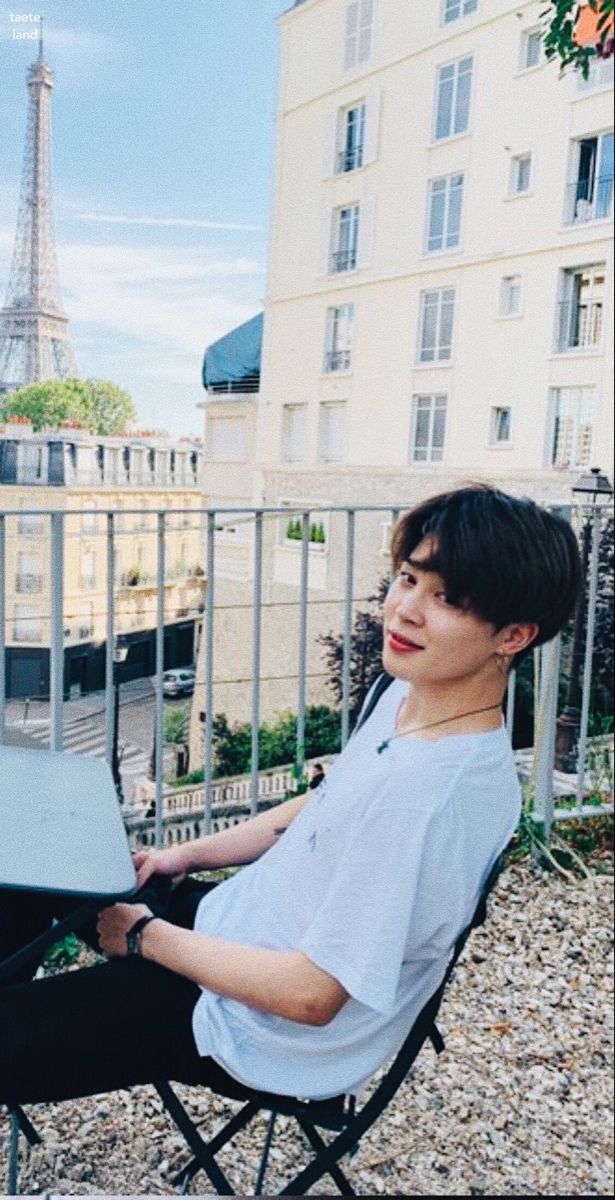 a person sitting in a chair with a laptop on their lap and the eiffel tower in the background