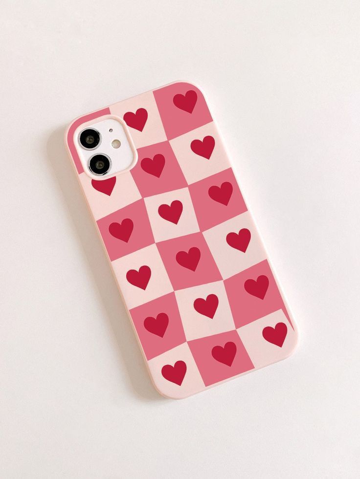 an iphone case with hearts on it sitting on a white table next to a cell phone