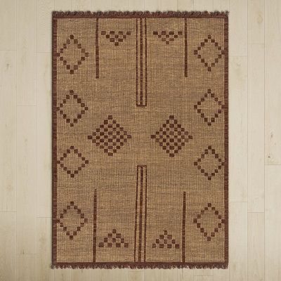 a brown rug with an intricate design on the bottom, and a cross - stitch pattern on the top