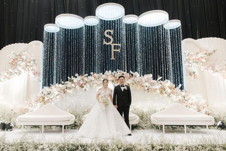 the newly married couple are posing in front of an elaborate stage with flowers and chandeliers