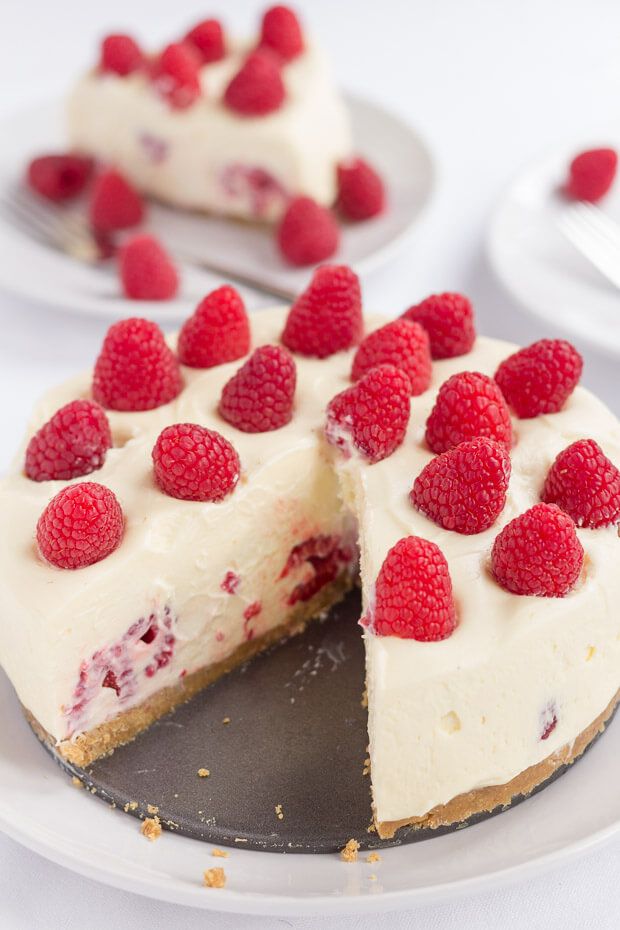 a cheesecake with raspberries is cut into slices and served on a plate