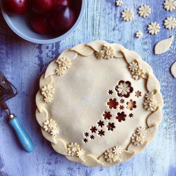 a pie sitting on top of a table next to a bowl of cherries