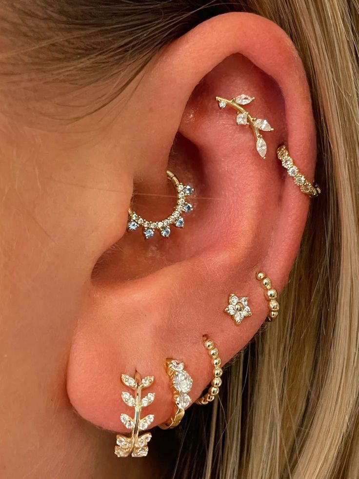 a close up of a person wearing ear piercings with leaves on it's sides