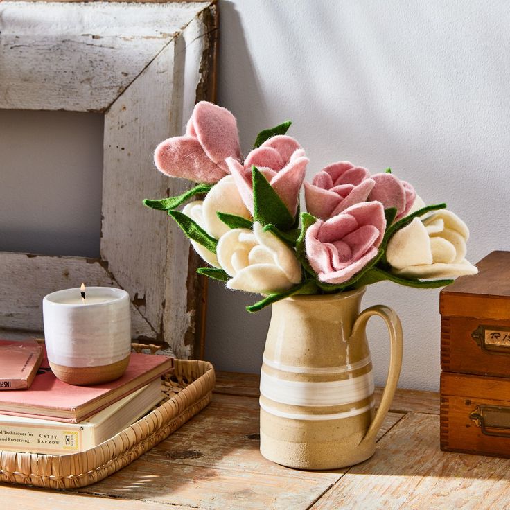 a vase filled with pink and white flowers on top of a table next to a book