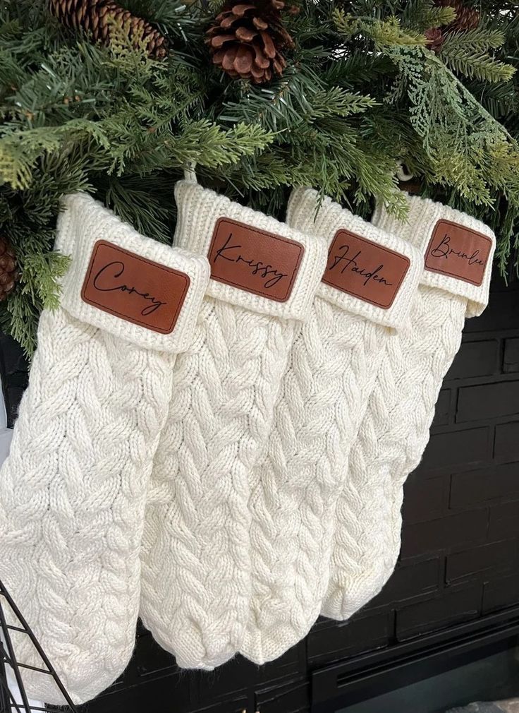 three white knit stockings hanging from a christmas tree