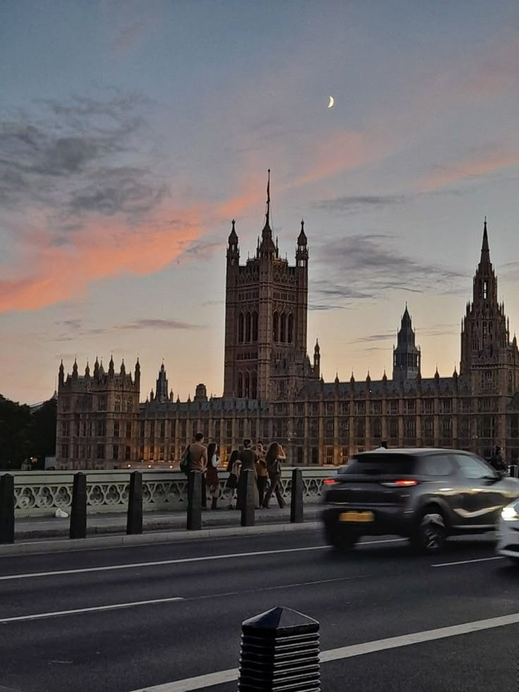 a car driving down the road in front of big ben and parliament at dusk, london