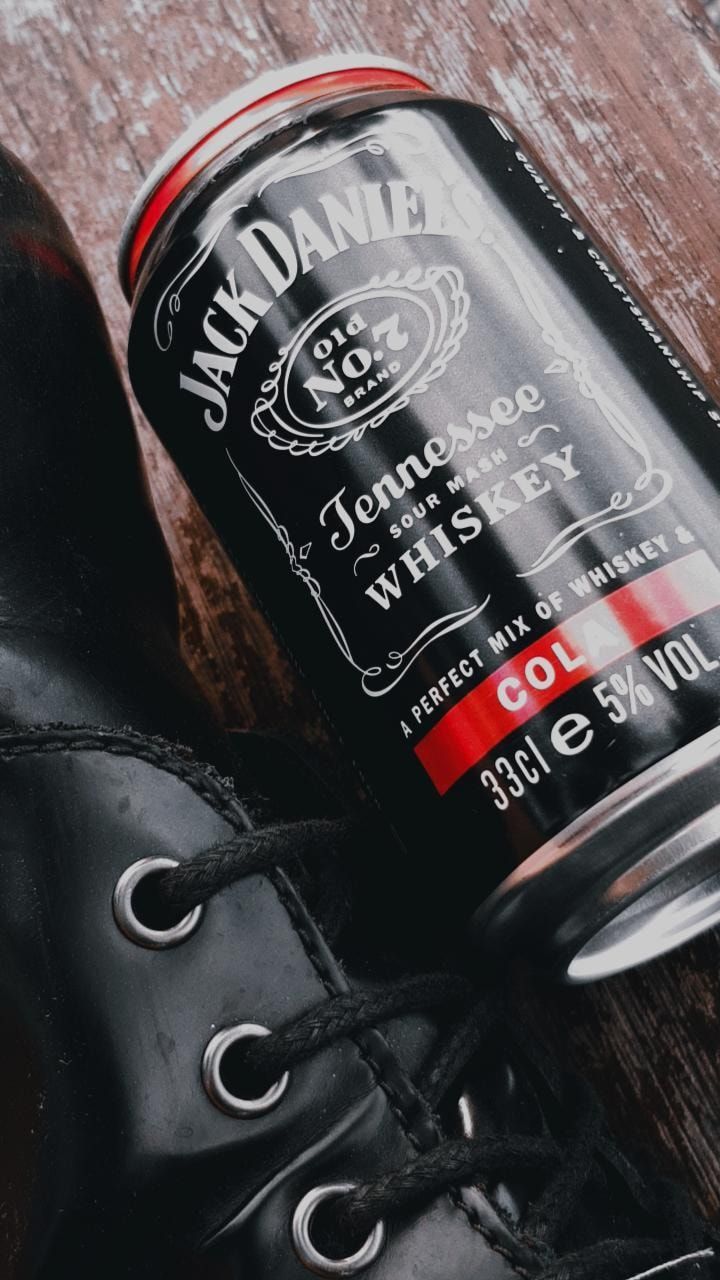 a can of jack daniels whiskey next to a pair of black boots